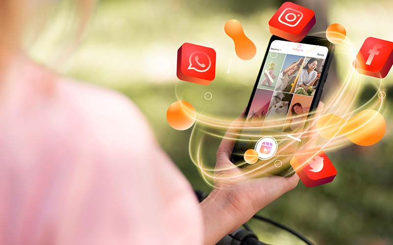 A woman holding a smartphone with social media icons displayed on the screen.