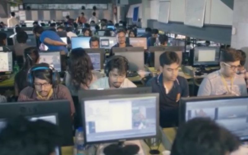 A diverse team of professionals diligently working on computers in a modern office setting.