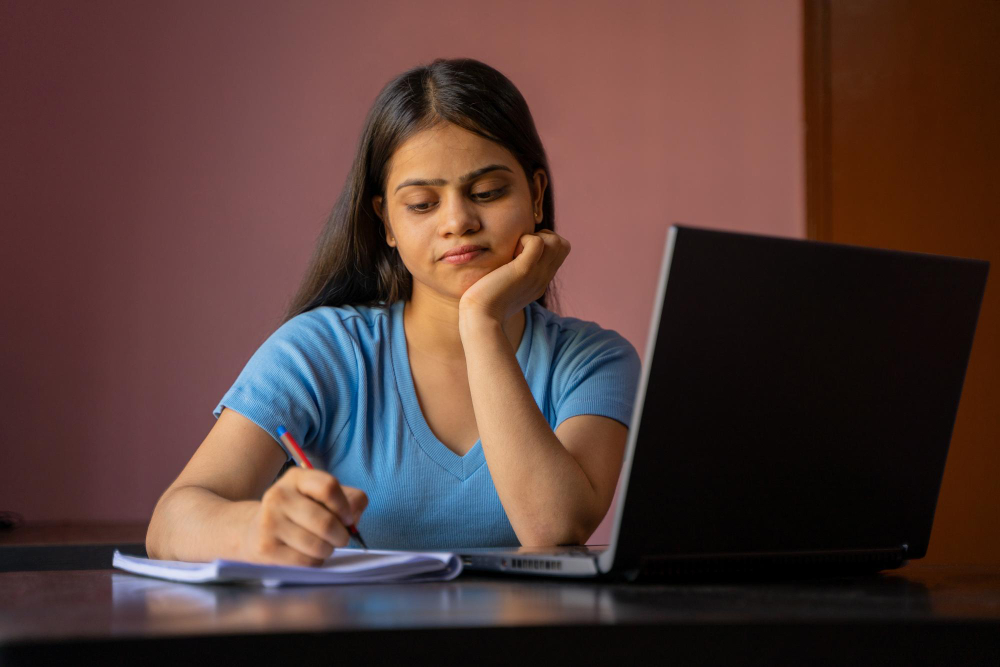 A woman sitting at a desk, focused on her laptop, working diligently