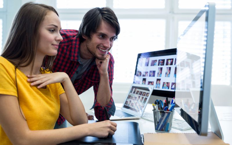 A man and woman focused on a computer screen.
